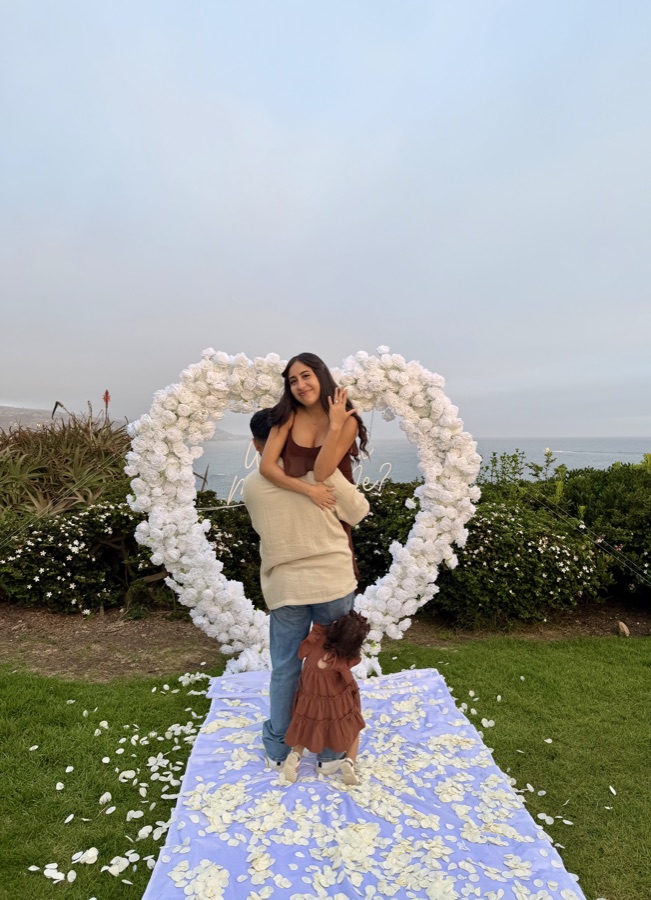 Family engagement photo with white floral heart arch by Big Moments Co.